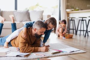 Man met kind liggen op het tapijt en zijn aan het tekenen